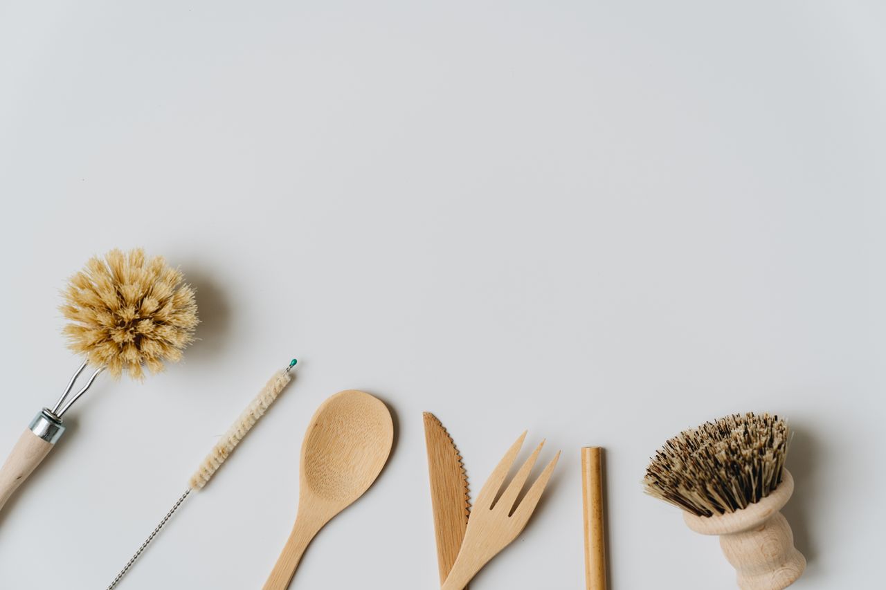 Des ustensiles et brosses de cuisine en bois durable sur fond blanc, mettant en avant un mode de vie respectueux de l’environnement.